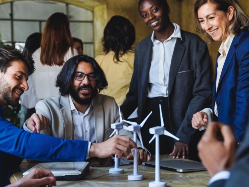 Happy business people work on sustainable renewable energy project inside office - Eco electricity