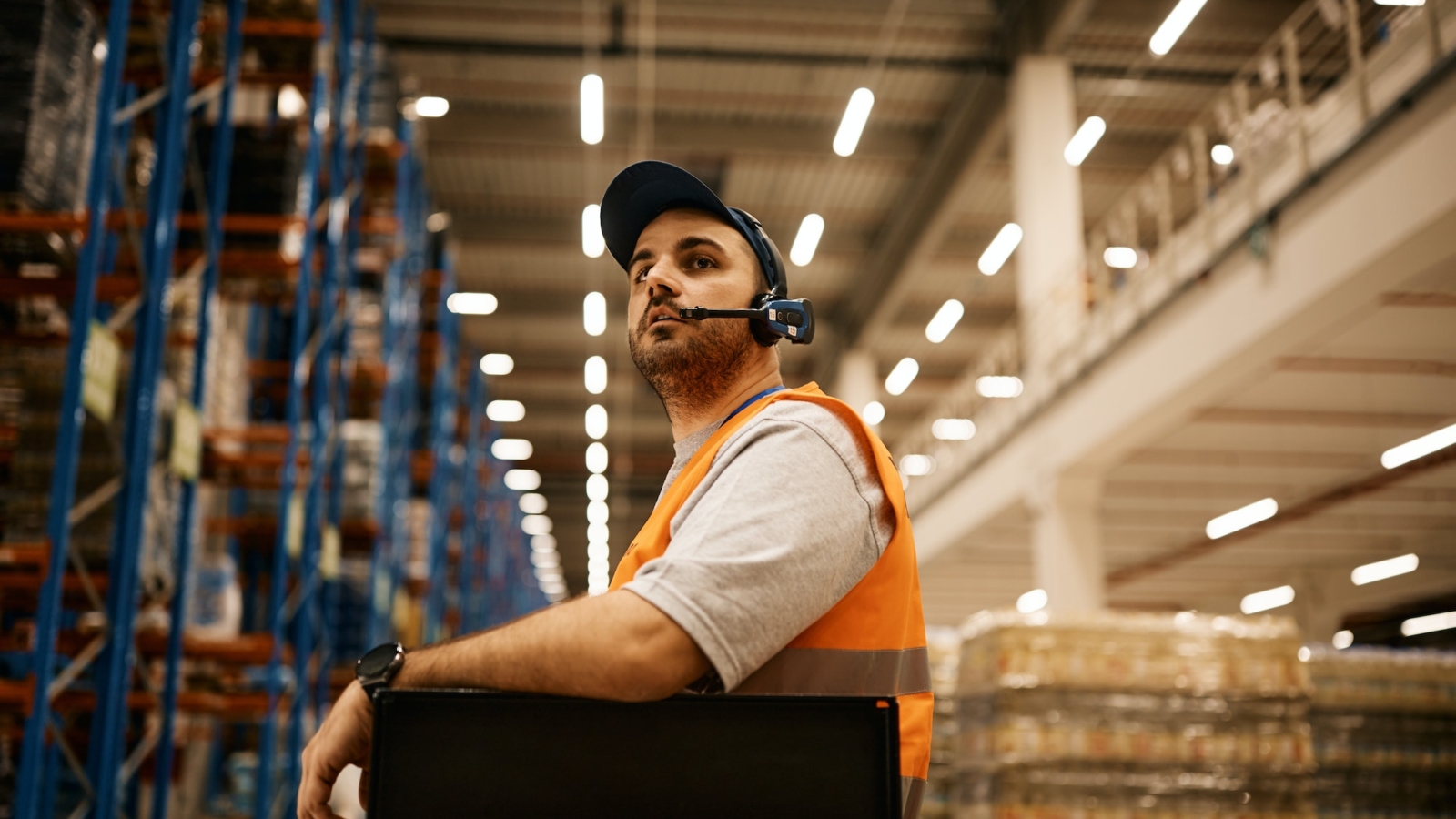 Warehouse worker driving forklift while working at storage compartment.