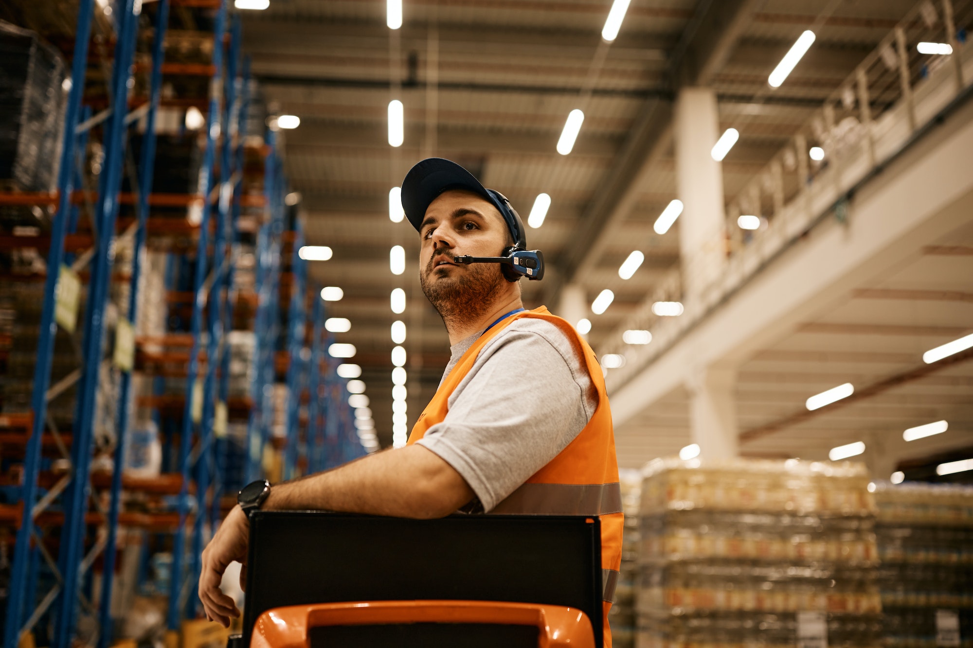 Warehouse worker driving forklift while working at storage compartment.